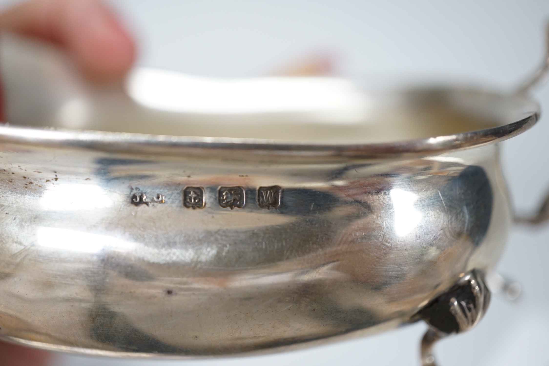 A George V silver sauceboat, Chester 1915, 189 grams, a later sauceboat with damaged handle, 82 grams and a shallow rectangular form sauceboat, 76 grams